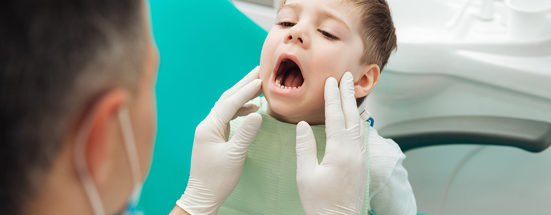 dentist-examining-teeth-of-little-boy-witting-PAK34DK